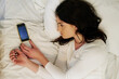 Tired, woman and smartphone in bed from break up with depression, anxiety and insomnia at home. Sad, female person and mockup with cellphone for worry, fear or stress at message for mental health