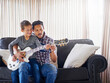 Father, child and guitar together on sofa for learning music, practice skill and talent development. Acoustic instrument, dad and son playing on couch in home training for bonding and entertainment
