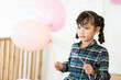 Cute young girl with braided hair holds pink balloons and have enjoy at her birthday
