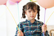 Cute young girl with braided hair holds pink balloons and have enjoy at her birthday