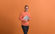 © Moon Safari - Portrait of confident male professional holding wireless computer and smiling on orange background