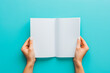 © VisualProduction - Woman hands holding folded blank paper sheet, empty booklet, double-pages book, magazine on light blue background. Mock up template. Top view