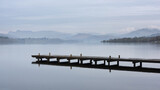 Fototapeta Londyn - Stunning peaceful landscape image of misty Spring morning over Windermere in Lake District and distant misty peaks