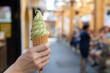 A person holding a green ice cream cone