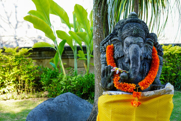 Statue of Lord Ganesha with a yellow garland, a tradition of Hindu Bali religious beliefs