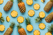 Top view of Colorful pattern of sliced pineapples on blue pastel background.