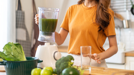 Wall Mural - Portrait of beauty healthy asian woman making green vegetables detox cleanse and green fruit smoothie with blender.young girl drinking glass of smoothie, fiber, chlorophyll in kitchen.Diet, healthy