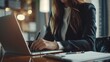 © Johannes - businesswoman in suit working on laptop and writing notes in notebook in office. close up hyper realistic