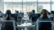 © Oulaphone - Call center workers with headsets sitting at desks and working on computers in a office space.