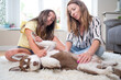 Mother and daughter sitting on carpet playing with her Siberian Husky puppy. Concept family with dog at home. High quality photo