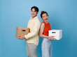 Happy young family asian couple man and woman moving boxes to their new home apartment isolated on blue background.