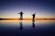 © jobi_pro - Silhouette of a happy couple jumping on the amazing mirror effect of Uyuni Salt Flats against sunset sky, Bolivia, South America