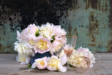 Fototapeta Krajobraz - Happy birthday greeting card concept; Bouquet of pink peonies and empty wineglasses on a rustic background; copy space