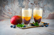 Traditional striped milk shake with mango, blueberries and buttermilk served in a glass as close-up on a design tray