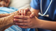 © nextzimost - A compassionate nurse holds the hands of an elderly patient, providing comfort and care in a hospital setting.