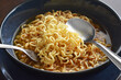 Instant noodles in a bowl with a spoon and a fork. Eating noodle soup. Homemade speed food. Asian dishes.