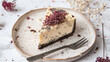 poppy seed cheesecake on plate with a fork against a white background with dried flowers
