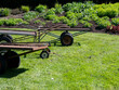 Metal garden carts standing on the lawn in front of a flowerbed in summer garden