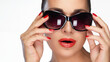 Fashion model wearing large sunglasses with vibrant red lipstick and nails, isolated on white