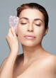 Close-up portrait of a woman with a rose quartz gua sha. Beauty and skin care for anti-aging and spa treatment, isolated on gray background