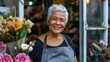 Latin woman with an apron and a smile stands in front of a flower shop. She is surrounded by a variety of flowers, including roses and daisies. Concept of warmth and happiness. Small business.