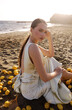 beautiful woman with dark hair in elegant white dress posing on the Cyprus beach with a lot of lemons