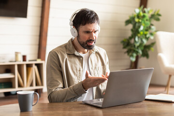 Aufkleber - A man sitting with headphones on, focusing on a laptop screen. He appears engaged and attentive to the information displayed on the computer, have video call