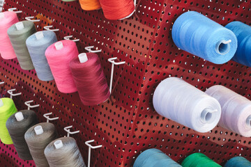 Aufkleber - A rack of colorful spools of thread. The spools are of various colors and sizes. The spools are arranged in a way that they are easily accessible and visible. Concept of organization and variety
