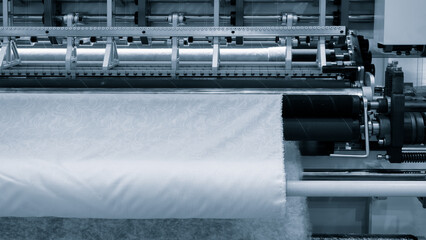 Wall Mural - A machine is weaving a fabric with many different colored threads. The machine is blue and white