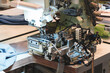 A sewing machine is in use, with a piece of fabric being sewn. The machine is black and silver, and the fabric is white. Scene is focused and precise