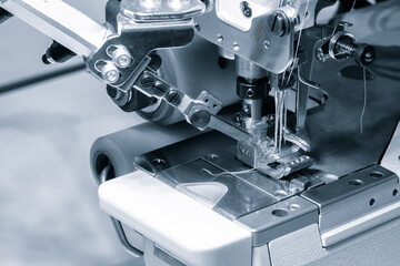Leinwandbilder - A sewing machine is in use, with a piece of fabric being sewn. The machine is black and silver, and the fabric is white. Scene is focused and precise