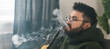 © satura_ - Banner bearded millennial or gen z man smoking hookah while relaxing on sofa at home copy space - chill time and resting concept