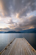 Wooden boat dock leading out to a lake with calm waters with a sunset sky. Harrison Lake, east of the lake are the Lillooet Ranges while to the west are the Douglas Ranges, British Columbia, Canada. 
