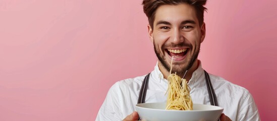 man eating Chinese noodles using a bowl against a wall background