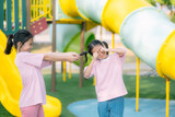 Fototapeta  - Two young girls are playing in a park, one of them has her hair in pigtails