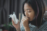Fototapeta  - A girl is holding a tissue and coughing