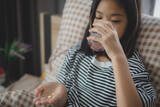 Fototapeta  - A girl is taking medicine and drinking water