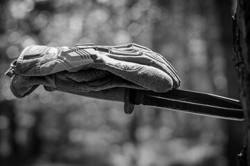 Tactical gloves on top of a tactical knife with a blade stuck in a tree.
Military ammunition, tactical equipment. Soldiery. Black and white photo