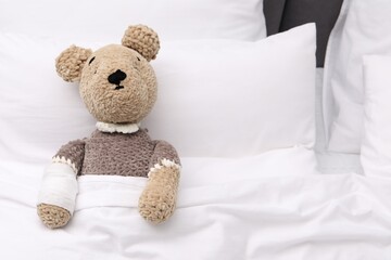 Canvas Print - Toy cute bear with bandage under blanket in bed