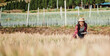 © Satori Studio - Concentrated female farmer with a straw hat evaluating the growth of crops in a vast farmland setting.