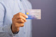 Man holding a blue credit card in front of a gray background.