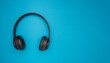 Top view of black wireless headphones on a blue background.