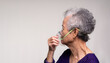 An elderly Asian woman using an oxygen mask.