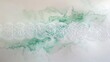 A piece of pristine, white lace, laid flat against a soft, pastel background, its symmetry interrupted by an elegant spill of emerald green watercolor, marrying the old with the new. 