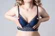 Blonde woman in blue push up bra on gray background, decollete area care