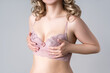 Blonde woman in pink push up bra on gray background, decollete area care