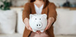 Woman hand holding piggy bank while sitting on sofa. Save money and financial investment