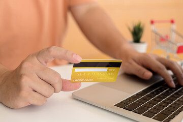 Wall Mural - Man holding a credit card and using laptop for online shopping