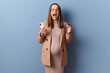 Excited amazed young adult pregnant woman wearing dress and jacket posing isolated over blue background making online payment enjoying internet shopping holding smartphone and credit card