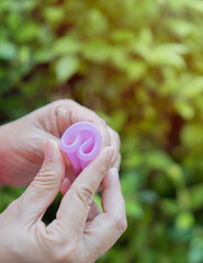 Close-up woman hands holding a mentrual cup and make it how to use a menstrual cup c form